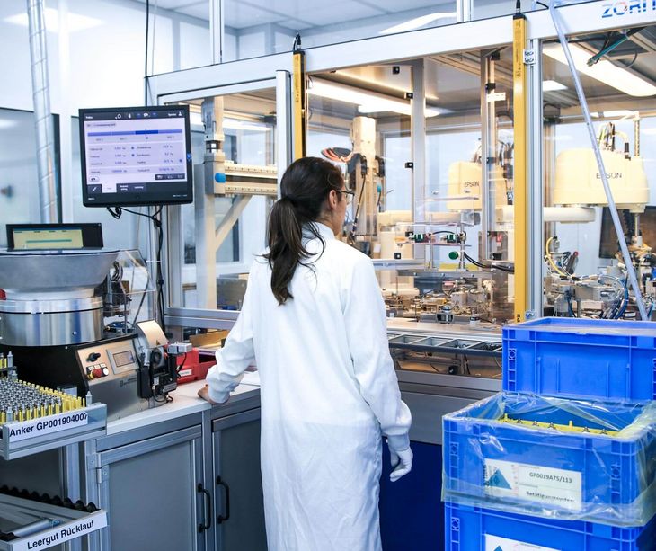 Eine Mitarbeiterin vor einer Maschine im Sauberraum bei Magnetbau Schramme